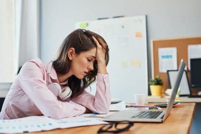 exhausted adult woman holding her head at her work desk