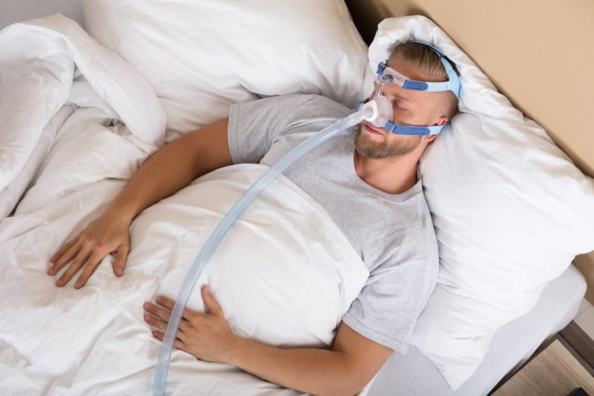 young adult male sleeping with cpap machine mask